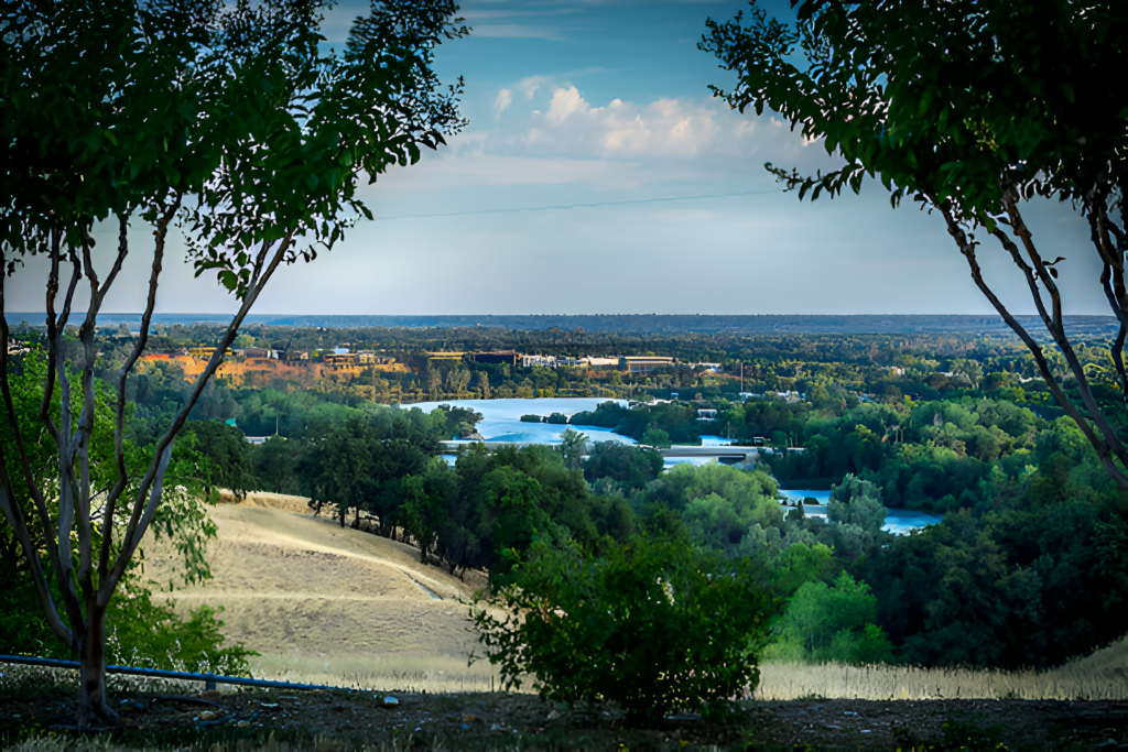 A breathtaking view of Elk Grove, California, featuring lush greenery, a winding river, and a scenic bridge.