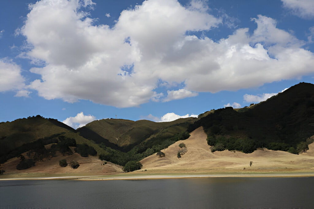 Morgan Hill, CA, landscape with green hills and a lake, offering a serene setting for luxury homes and real estate investment.